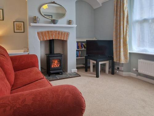 ein Wohnzimmer mit einem Kamin und einem roten Sofa in der Unterkunft Allington Cottage in Bridport