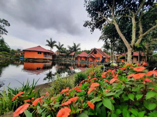 a group of houses next to a river with flowers at Cabañas Mountain River Lake Inn in Nueva California