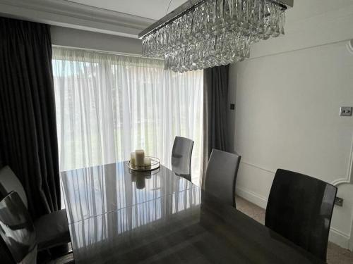 a dining room with a glass table and a chandelier at Lovely 3 bedroom house in Borehamwood . in Borehamwood