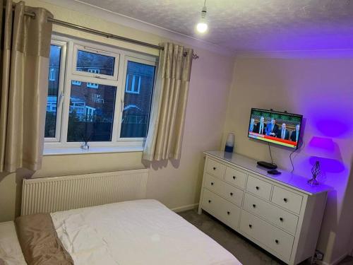 a bedroom with a bed and a tv on a dresser at Lovely 3 bedroom house in Borehamwood . in Borehamwood