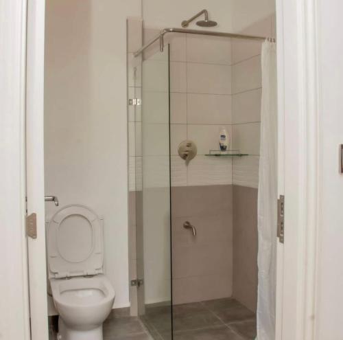 a bathroom with a toilet and a glass shower at La Maison II- Two Bedroom in Tatu City, Nairobi in Nairobi