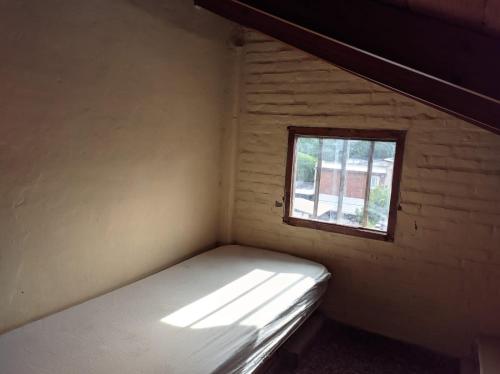 Habitación pequeña con cama y ventana en departamento en Valeria del mar en Valeria del Mar