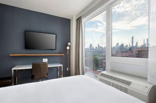 a bedroom with a large window with a view of the city at TownePlace Suites by Marriott New York Long Island City in Queens