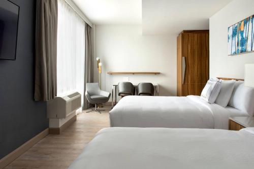 a hotel room with two beds and a table and chairs at TownePlace Suites by Marriott New York Long Island City in Queens
