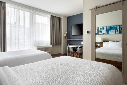 a hotel room with two beds and a desk at TownePlace Suites by Marriott New York Long Island City in Queens