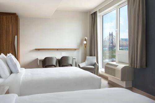 a hotel room with two beds and a window at TownePlace Suites by Marriott New York Long Island City in Queens