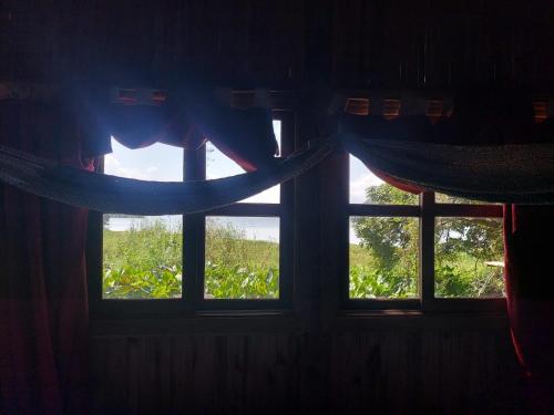 two windows in a room with curtains and a bed at Reserva Ecologica Nanciyaga in Catemaco
