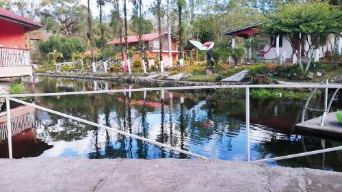 a pond with a white railing next to a house at Cabañas Mountain River Lake Inn in Nueva California