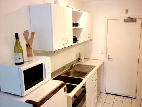 a kitchen with a microwave and a sink at Studio Apartment in Auckland CBD in Auckland
