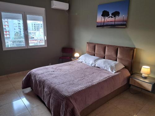 ein Schlafzimmer mit einem Bett und zwei Fenstern in der Unterkunft Vlora Bay in Vlorë