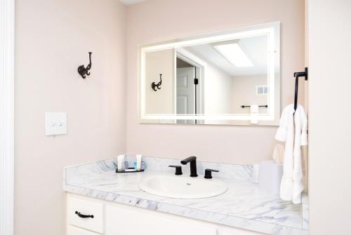 Baño blanco con lavabo y espejo en Bella Vista Hotel & Suites, en Lynchburg