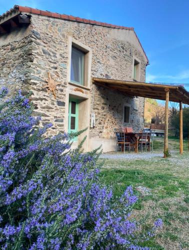 a stone house with a table and purple flowers at SKY HOUSE Experience in Orco Feglino