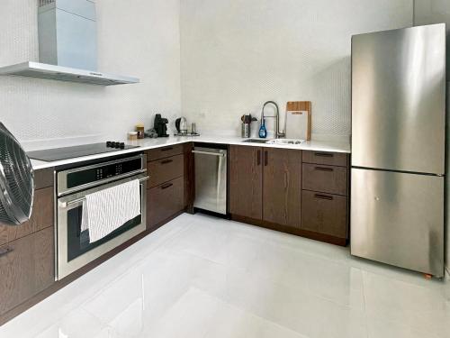 a kitchen with a stainless steel refrigerator and wooden cabinets at Stunning 3-Bedroom Beachside Apartment in San Juan