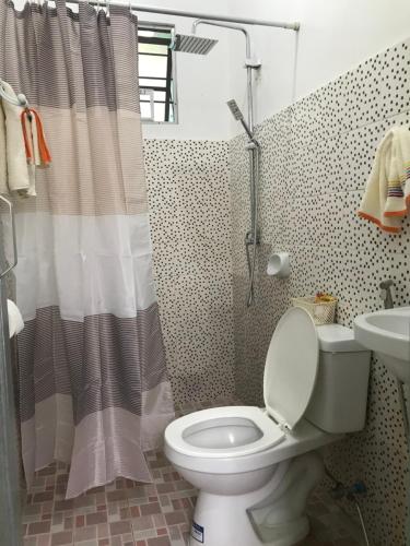 a bathroom with a toilet and a shower curtain at GGGO RESIDENCES, Studio 103, pet friendly in Sorsogon