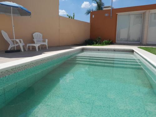 una piscina con 2 sillas y una sombrilla en CASA QUINTA La Donna con DESAYUNO en Villa María