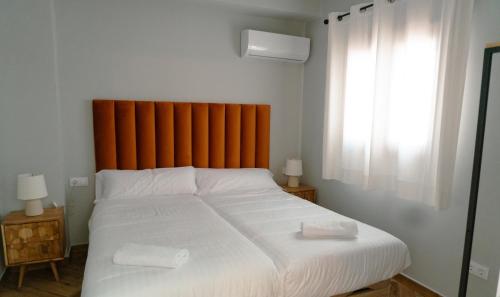 a bedroom with a large white bed with an orange headboard at La Banda Rooftop Hostel in Seville