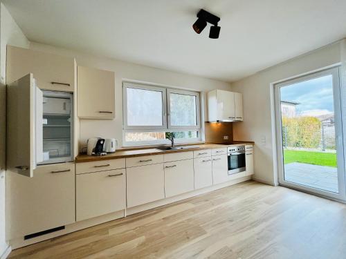 een keuken met witte kasten en een groot raam bij MyBLEISURE Premium Apartment mit Küche und Netflix nahe Heidelberg I SAP, MLP, Unternehmen im Rhein-Neckar-Kreis in Rauenberg