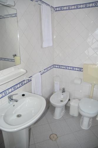 a white bathroom with a sink and a toilet at Residencial A Doca in Faro