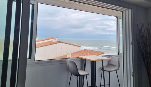 uma janela com duas cadeiras e uma mesa com vista para o oceano em Eau Bleue d'Eden em Saint-Hilaire-de-Riez