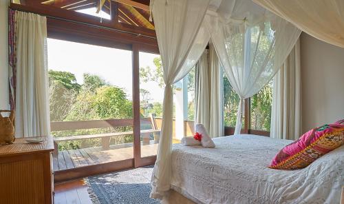 a bedroom with a canopy bed and a large window at Casa Bali Ibira in Imbituba