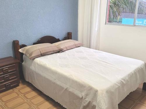 a bedroom with a bed with a white comforter and a window at Apartamento Brejatuba Beira Mar in Guaratuba