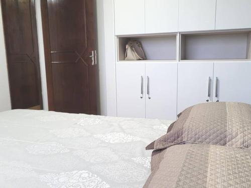 a bedroom with a white bed with white cabinets at Apartamento Brejatuba Beira Mar in Guaratuba