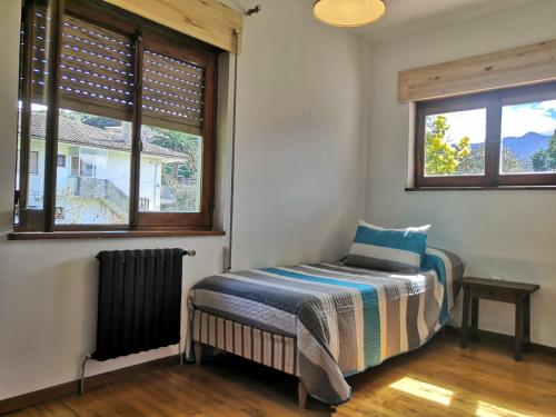 a bedroom with a bed and two windows at Chalet Las Llamas in Llanes