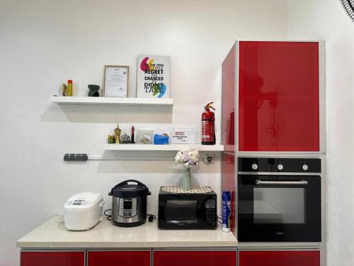 a kitchen with red cabinets and a black microwave at Bandar Melaka Family Bungalow Private Pool BBQ WiFi Netflix in Melaka