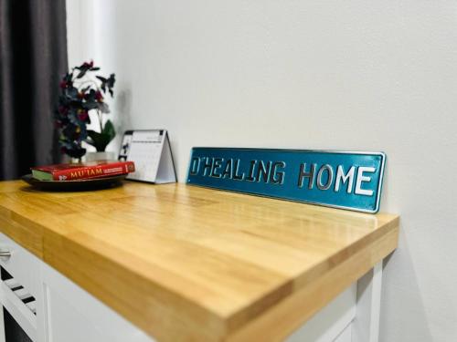 a blue sign that reads healing home on a wooden counter at Bandar Melaka Family Bungalow Private Pool BBQ WiFi Netflix in Melaka