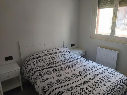 a bedroom with a bed with a black and white comforter at Precioso apartamento en Bilbao. in Galdakao