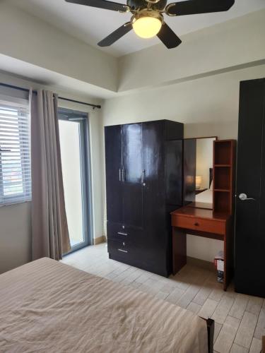 a bedroom with a bed and a desk and a ceiling fan at Manhattan Plaza Tower 1 in Manila