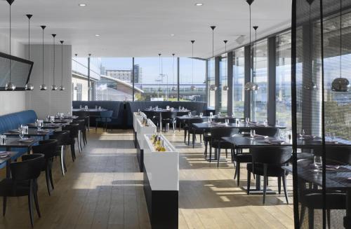 a restaurant with tables and chairs and large windows at Radisson Blu Manchester Airport in Hale