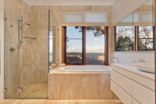 a bathroom with a tub and a shower with a window at Shirri Mirri in Leura