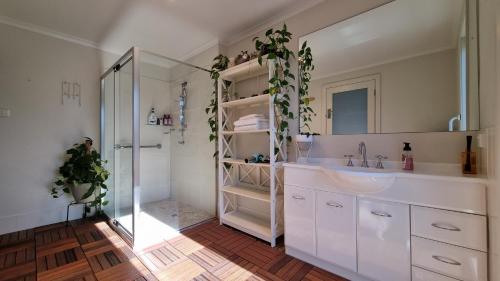 y baño blanco con lavabo y ducha. en Guest Suite in Duffy en Weston Creek