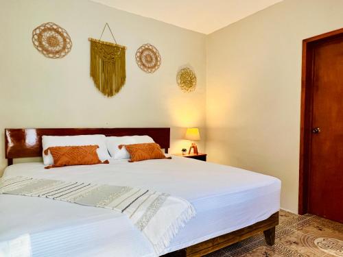 - une chambre avec un grand lit blanc et des oreillers orange dans l'établissement CASA VICTORIA, à Chichén Itzá