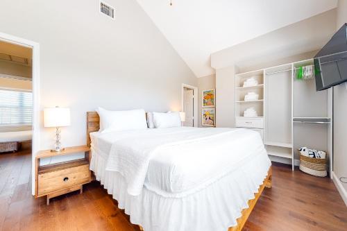 a white bedroom with a large bed and a tv at The Tipsy Mermaid in Key West