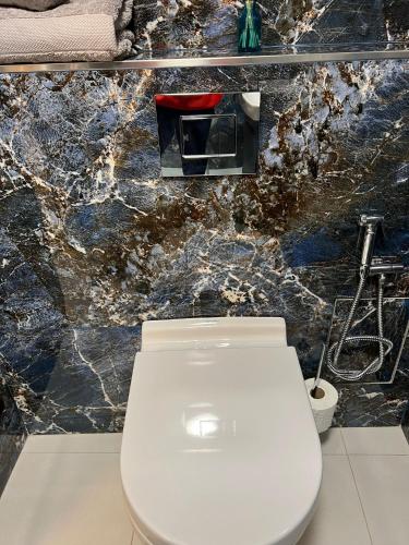 a white toilet in a bathroom with a marble wall at Garden View in Northfleet
