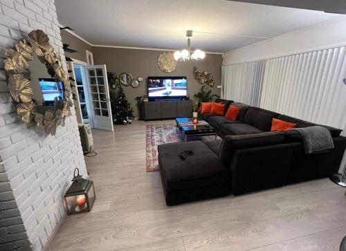 ein Wohnzimmer mit einem schwarzen Sofa und einem TV in der Unterkunft Family House in Drammen