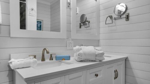 ein weißes Badezimmer mit einem Waschbecken, Spiegeln und Handtüchern in der Unterkunft Serena's Secret in Panama City Beach