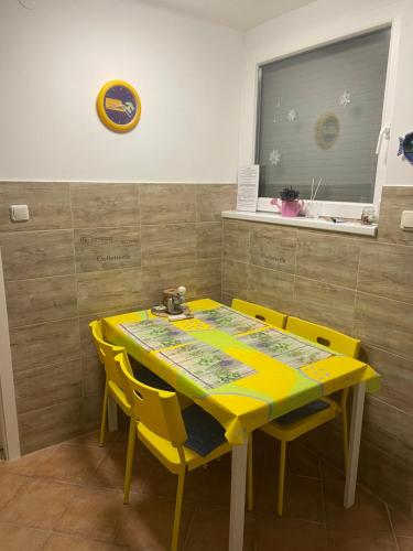 uma mesa amarela com cadeiras amarelas num quarto em Viktória Apartman em Balatonalmádi