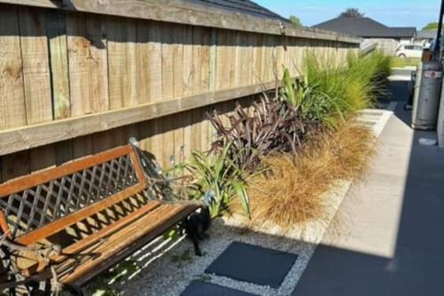 a wooden bench sitting next to a fence at Guest House in Tepuke in Te Puke