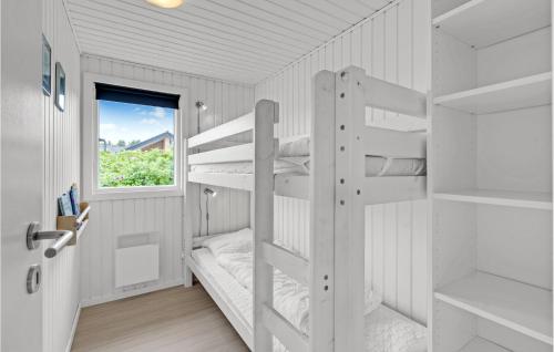 4 Bedroom Beautiful Home In Hvide Sande في Nørre Lyngvig: سرير بطابقين أبيض في غرفة مع نافذة