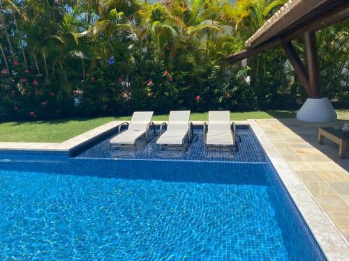 a swimming pool with three lounge chairs next to a swimming pool at CASA CONDOMÍNIO IBEROSTATE - RESORT IBEROSTAR in Praia do Forte