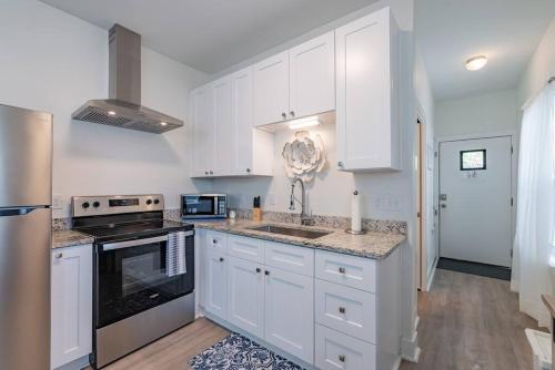 uma cozinha com armários brancos e um forno com placa de fogão em Secret Garden em San Antonio