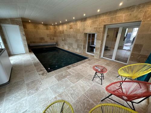 a swimming pool in a room with chairs and a table at Gite 5 chambres, piscine intérieure, proche du Der 