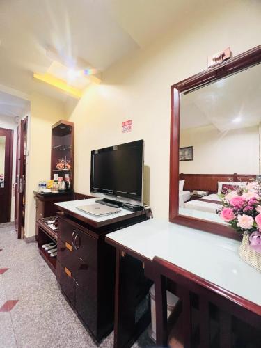 a room with a large mirror and a desk with a television at LUCASTA SAIGON Hotel in Ho Chi Minh City