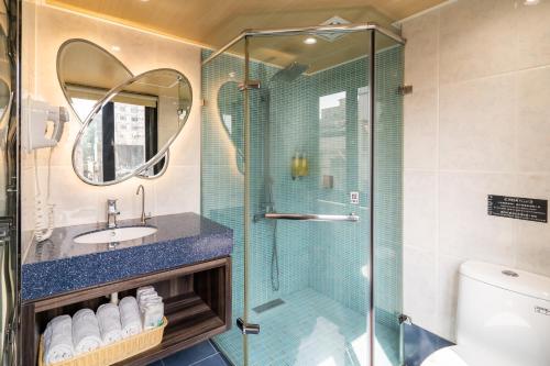 ein Bad mit einer Glasdusche und einem Waschbecken in der Unterkunft The Cloud Hotel in Kaohsiung