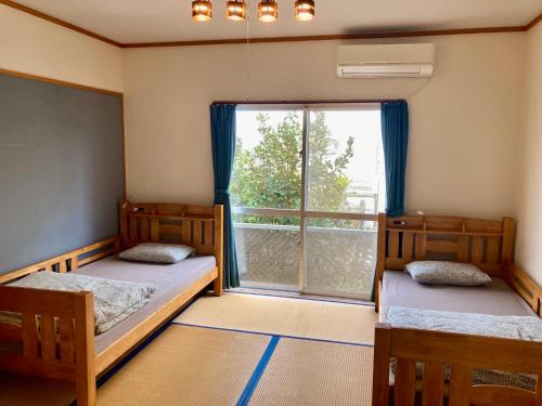 dwa łóżka w pokoju z dużym oknem w obiekcie Life is a Journey w mieście Yomitan