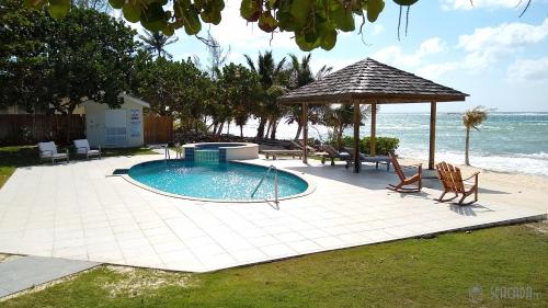 a swimming pool with a gazebo next to the ocean at Seacada- Beachfront - Pool - Panoramic Sunsets in George Town