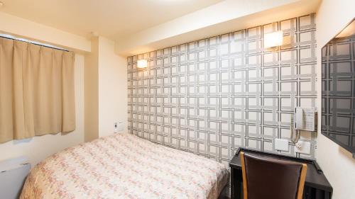 um quarto com uma cama, uma secretária e uma parede em Yokohama Town Hotel em Yokohama